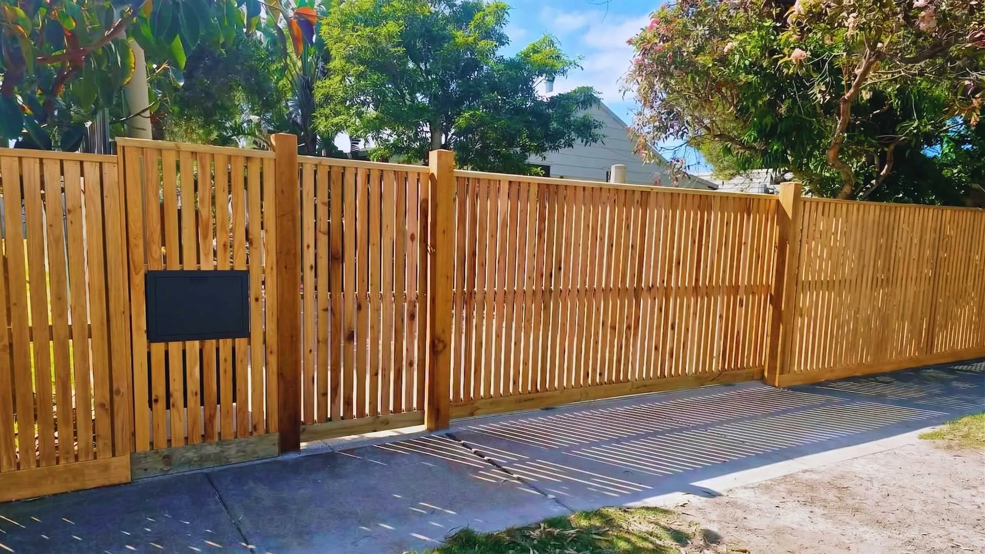 Timber slat fence and matching sliding driveway gate built by Upright Fencing